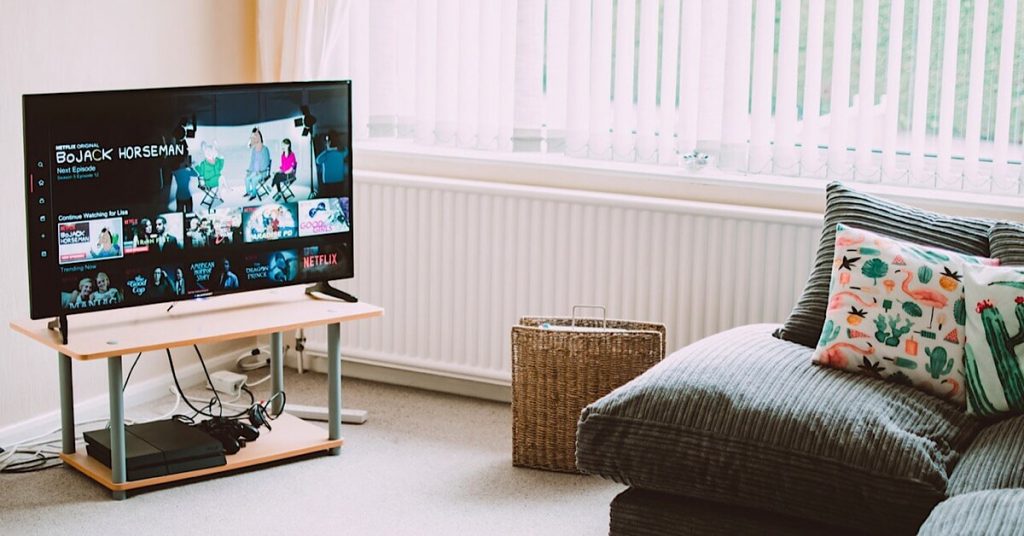 A smart TV on a stand with Netflix on the screen.