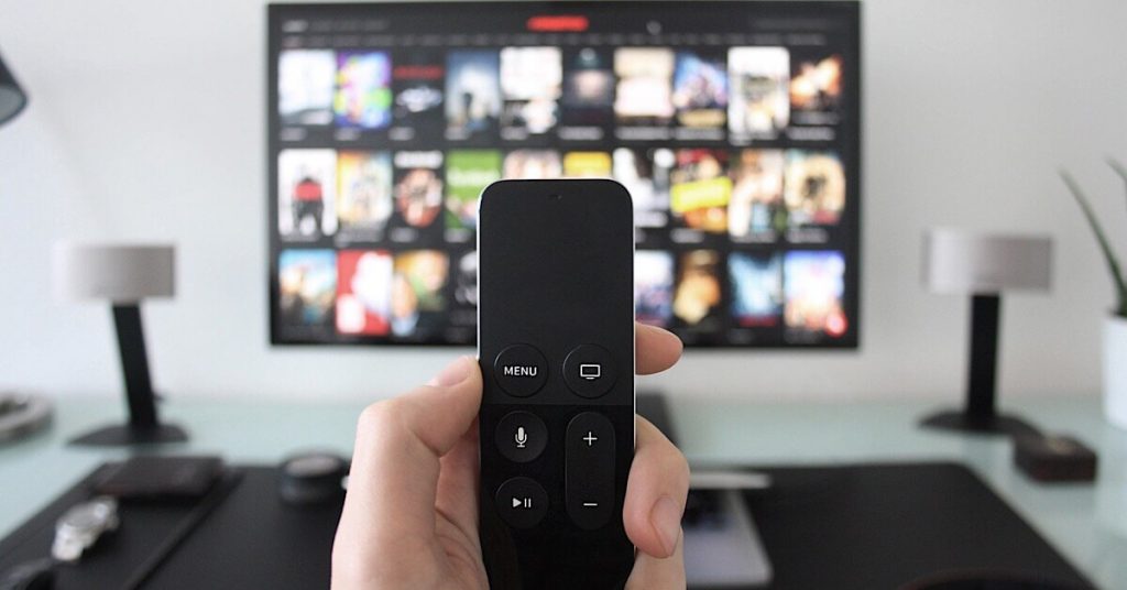 Someone holding a remote in front of a smart TV.