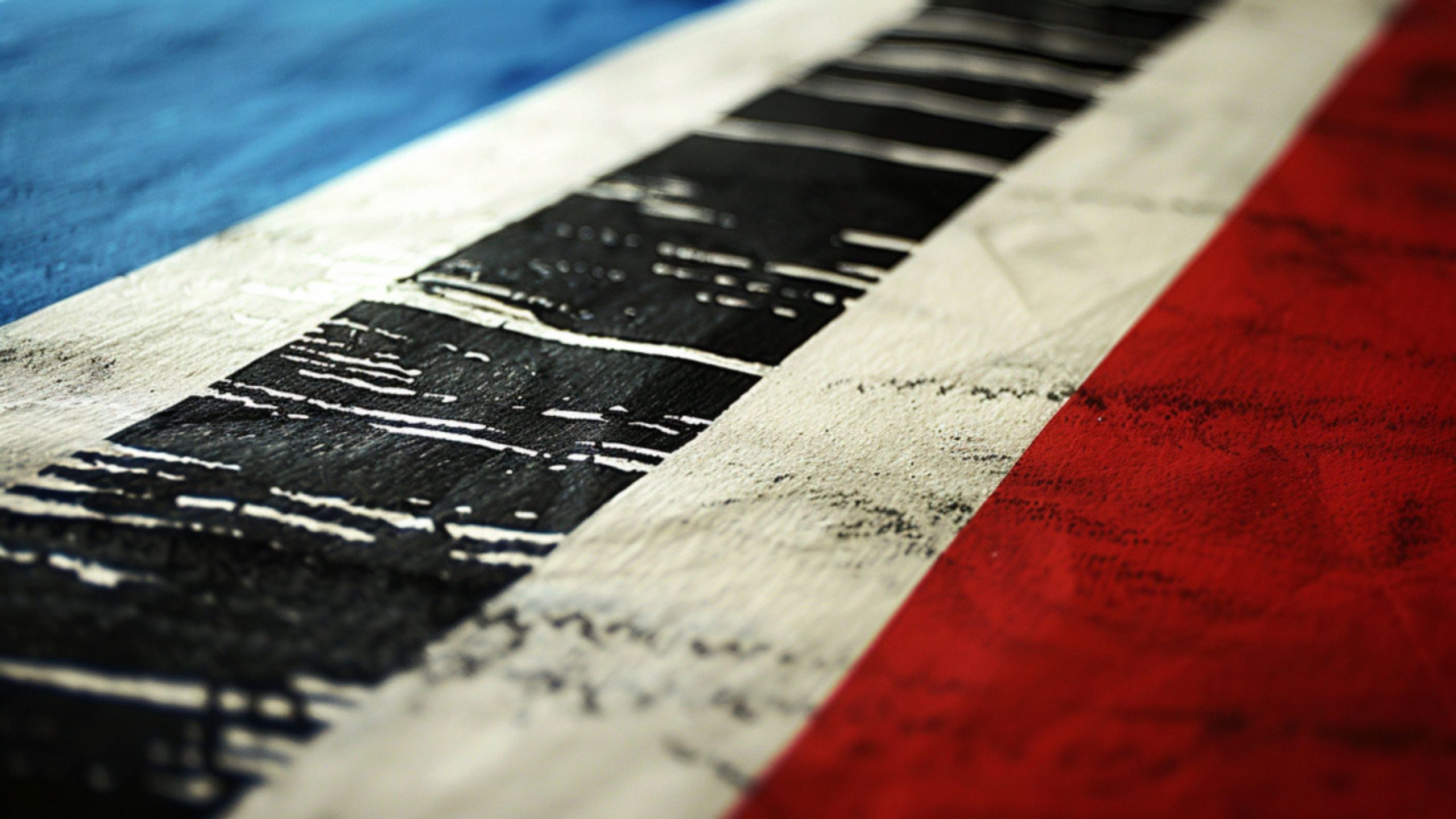 Worn painted surface with blue, white and red stripes and distressed black rectangular marks on the white band.