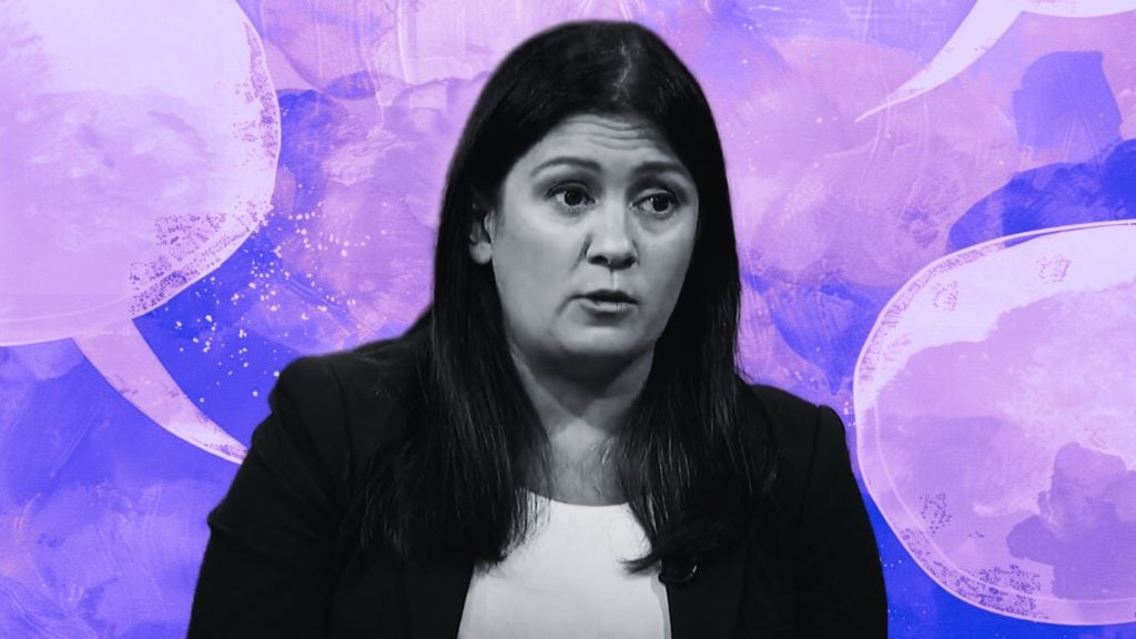 Lisa Nandy with a serious expression speaks in front of a purple background with speech bubbles.