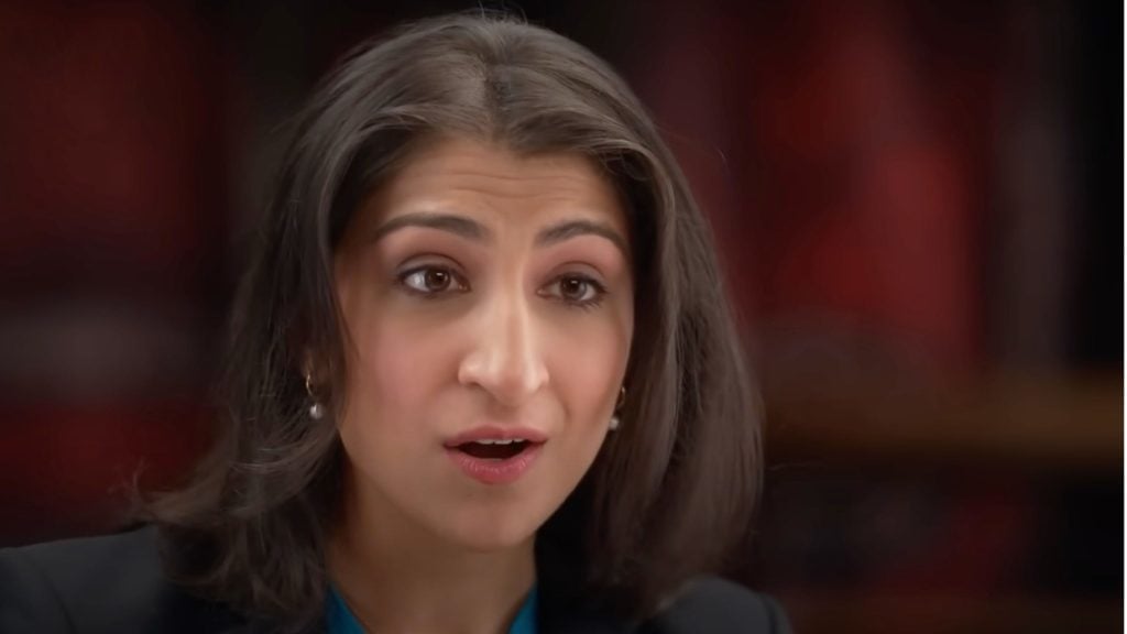 Lina Khan with shoulder-length dark hair and pearl earrings speaking, with a blurred background.