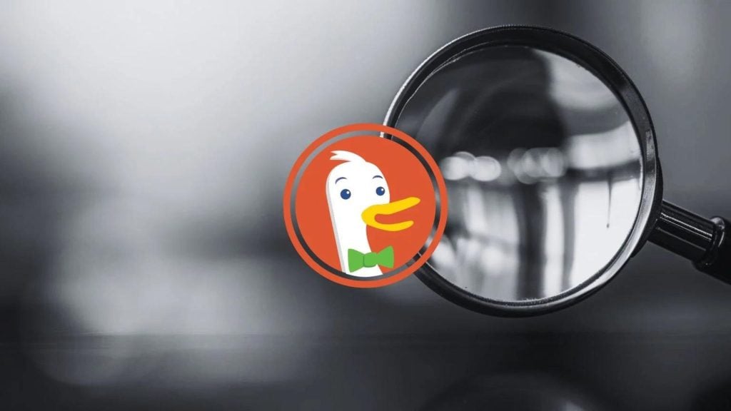 DuckDuckGo logo in front of a blurred black and white magnifying glass.