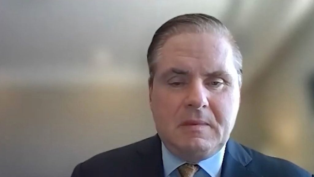 Greg Essensa in a suit during a video call.