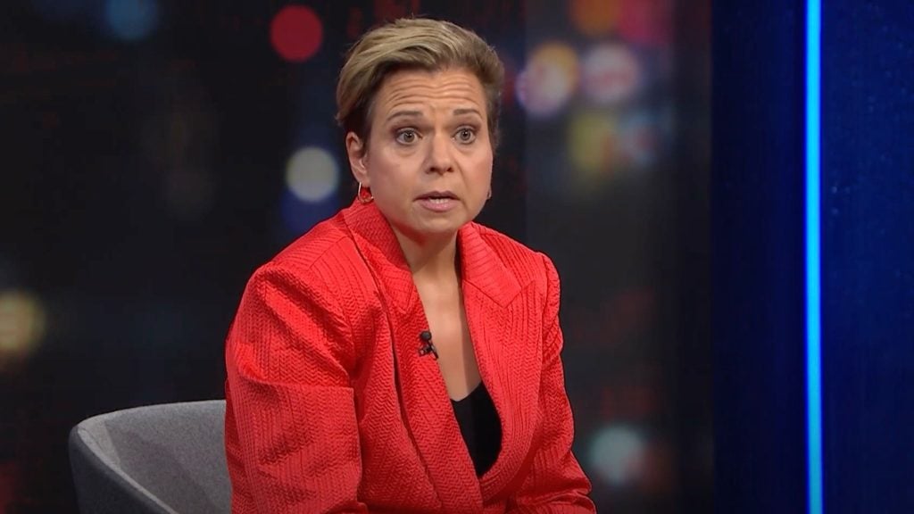 Michelle Rowland in a red jacket sitting in front of a blurred background.