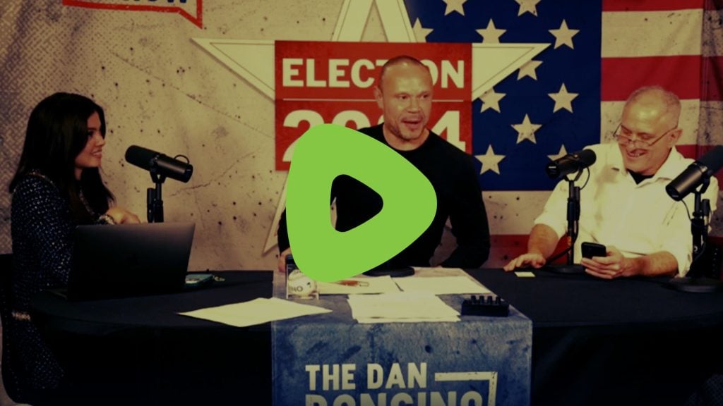 A podcast recording featuring Dan Bongino sitting at a table with microphones, with election-themed decorations in the background.