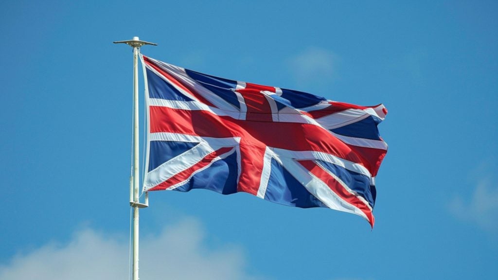 The Union Jack flag waving against a blue sky.