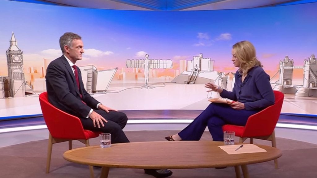 Kuenssberg and Kyle seated in red chairs on a TV set with a backdrop of sketched city landmarks.