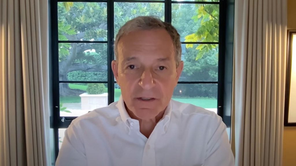 Disney CEO Bob Iger in a white shirt sitting indoors, with a large window showing a green garden in the background.