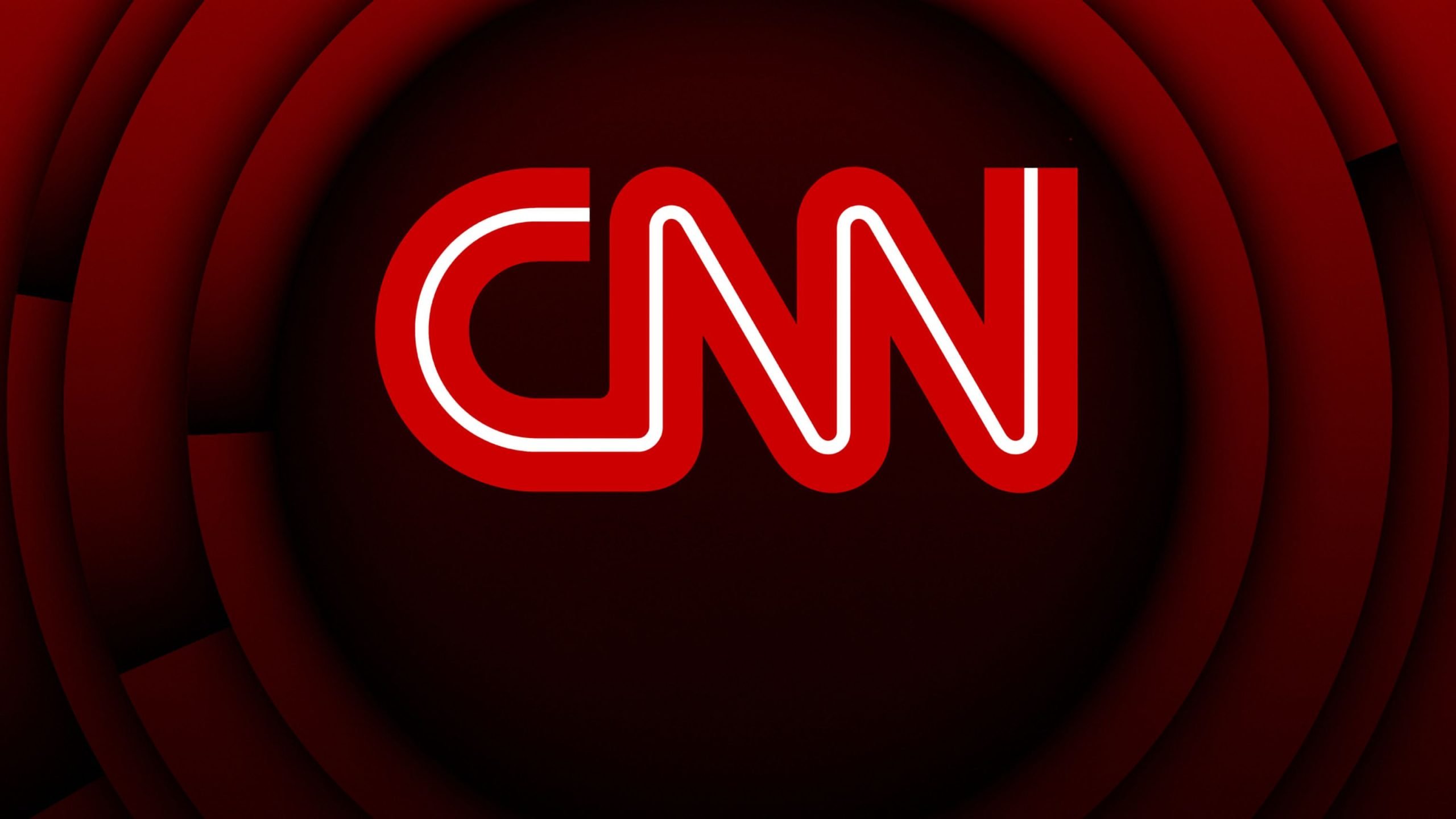 CNN logo on a dark red, concentric circular background.