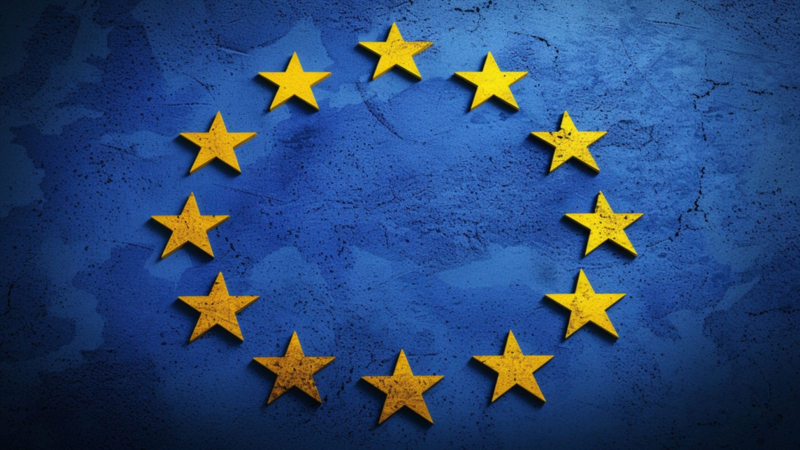 European Union flag with twelve yellow stars in a circle on a textured blue background.