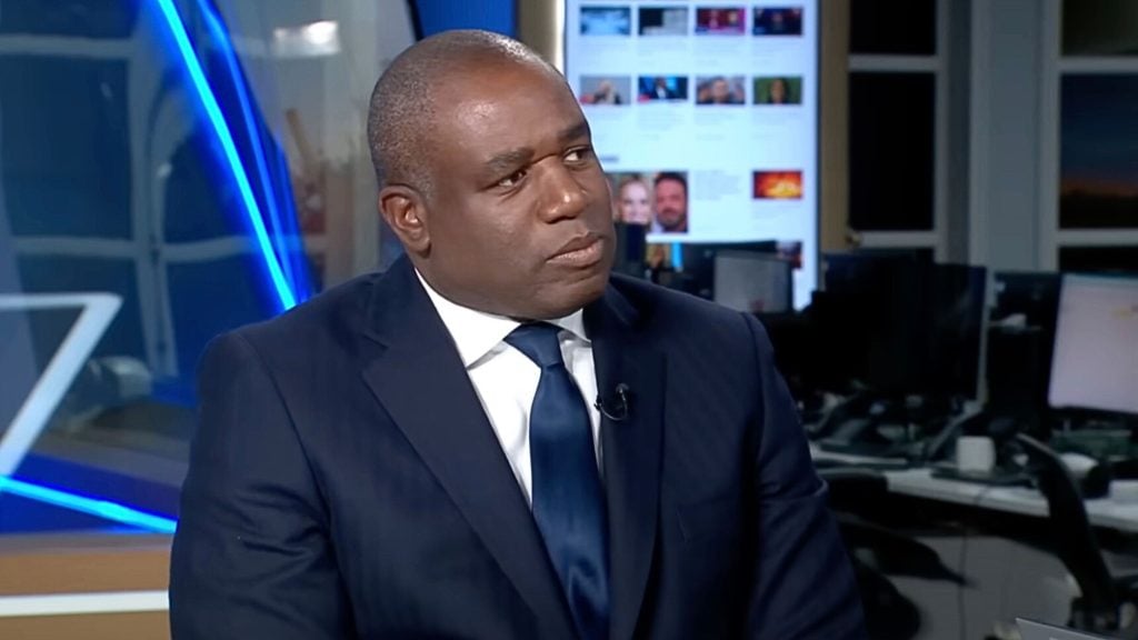 Lammy in a suit and tie appears thoughtful during a TV interview.