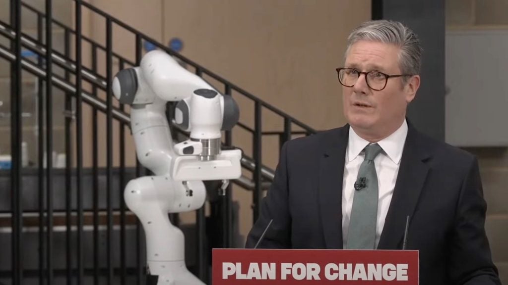 Starmer is speaking at a podium labeled "PLAN FOR CHANGE," with a robotic arm visible in the background.