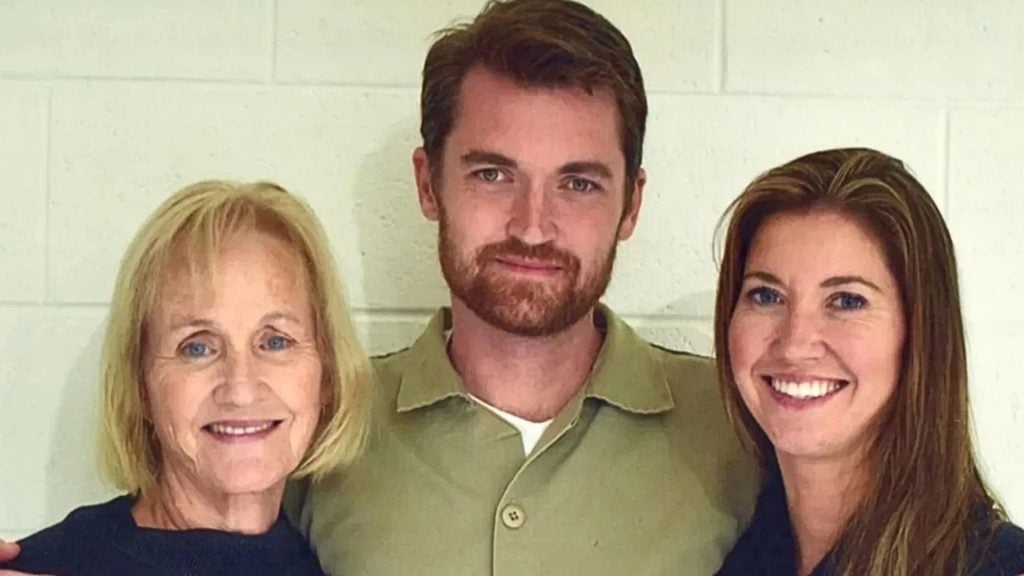 Ulbricht smiling at the camera in front of a white brick wall.