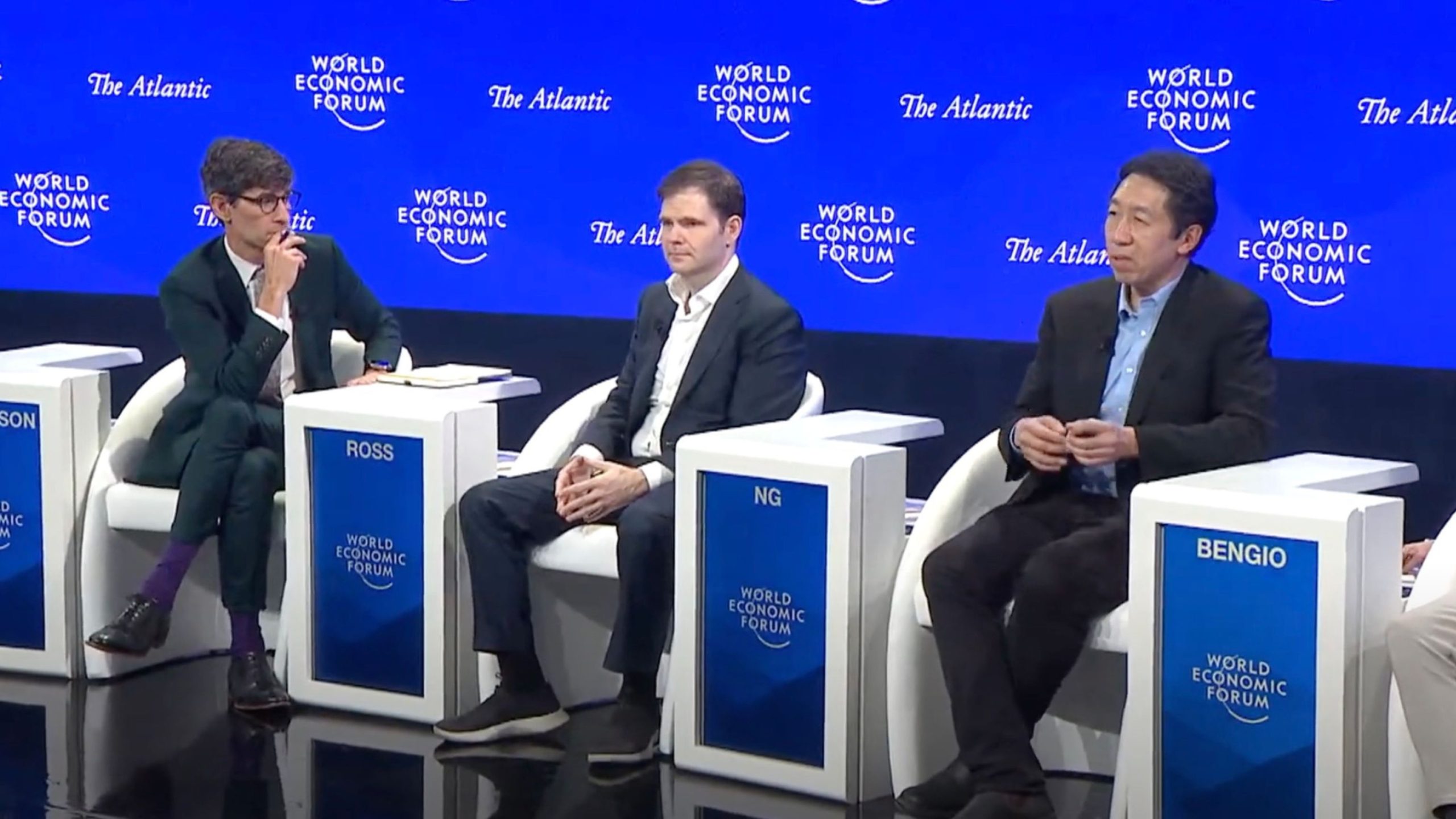 Three individuals seated on a stage panel at the World Economic Forum event, with blue backgrounds and name tags reading Ross, Ng, and Bengio.