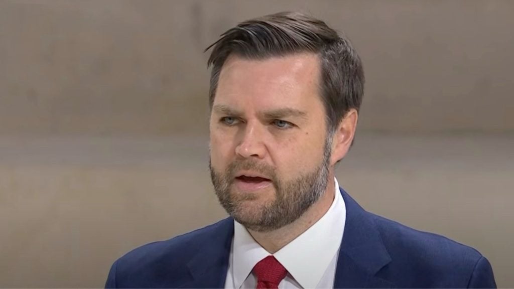 JD Vance in a suit and red tie speaking.