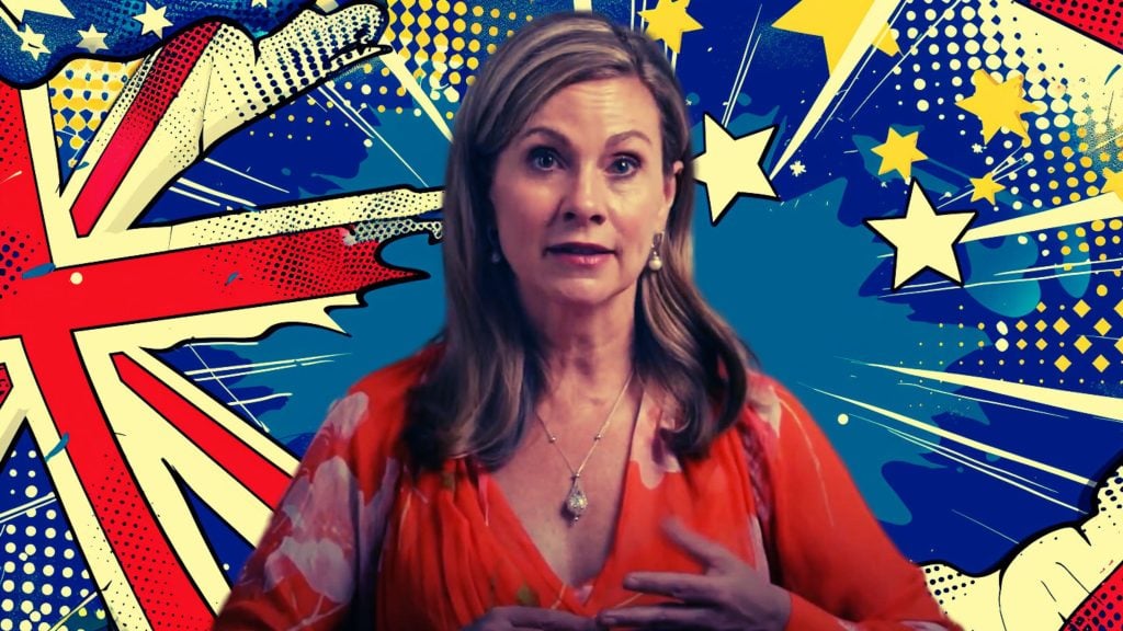 Grant in an orange dress stands in front of a colorful comic book-style background with stars and stripes.