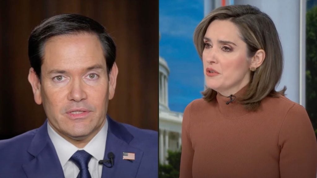 Split-screen image showing two individuals in a professional setting; the person on the left is Rubio wearing a blue suit with an American flag pin, while the person on the right is Brennan, dressed in a brown turtleneck with short hair, possibly engaged in discussion.