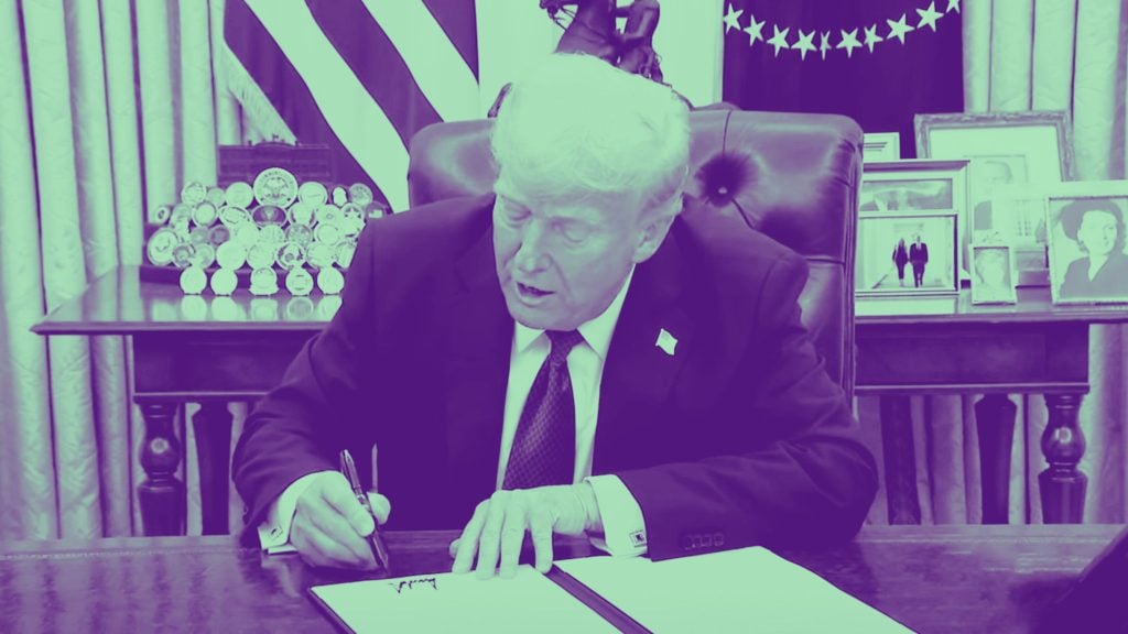 President Trump at a desk signing a document, with photos and medals in the background, in a monochromatic purple tone.