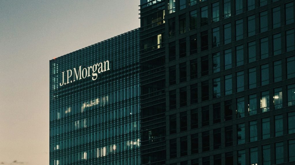 A building with the J.P. Morgan logo prominently displayed on the facade, featuring lit windows in the evening light.