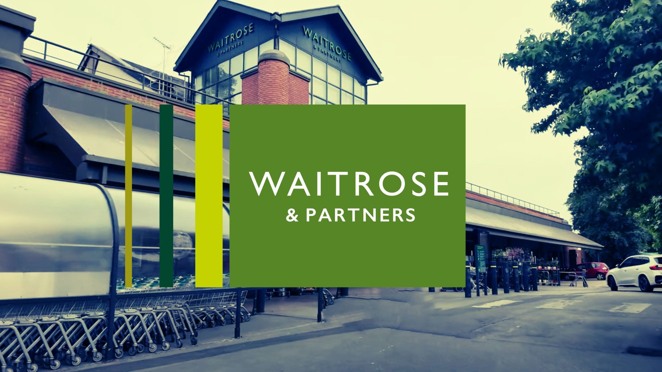 Exterior view of a Waitrose & Partners supermarket with parked shopping carts and a green logo displayed prominently in the foreground.