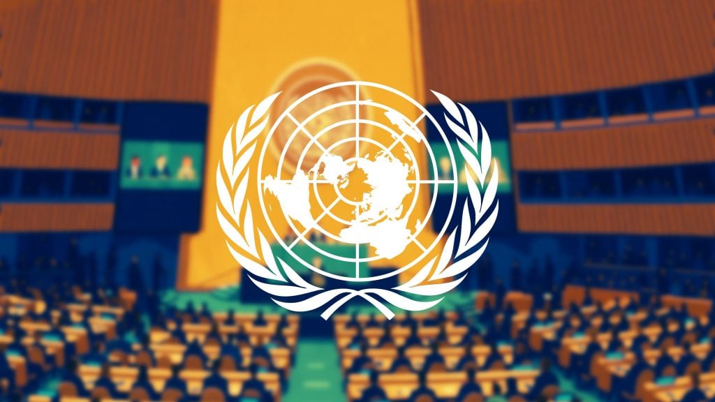 Blurry conference hall filled with attendees, overlaid with a prominent white United Nations emblem featuring a world map encircled by olive branches.