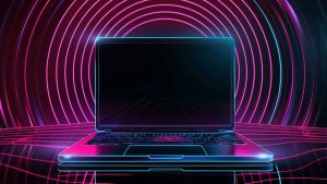 A laptop with a neon color outline in front of a futuristic background featuring concentric circles of pink light on a dark surface.