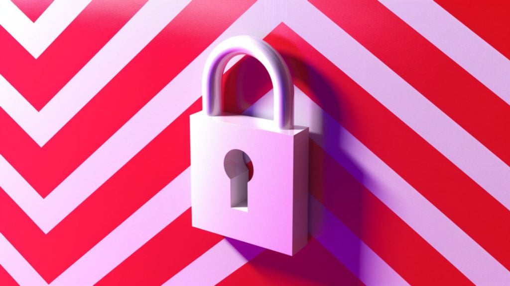 White padlock with a keyhole casting a shadow on a red and white chevron-patterned wall.