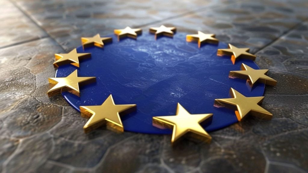 Close-up of the European Union flag with twelve golden stars arranged in a circle on a blue circular background, placed on a textured stone surface.