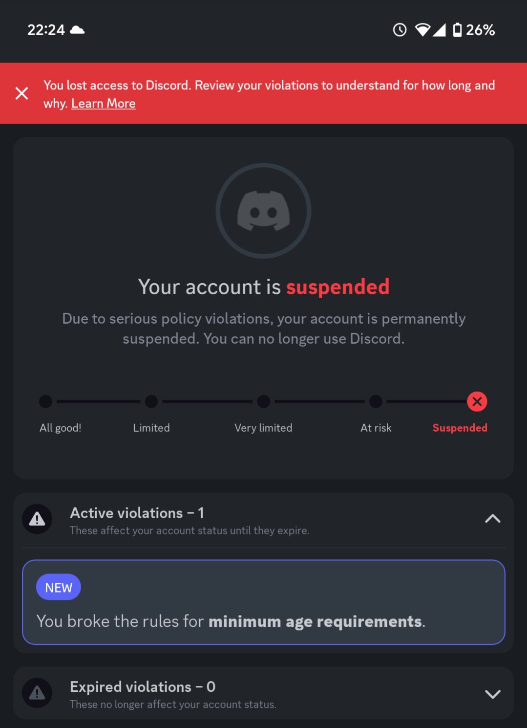 Smartphone screen showing a Discord account suspension notification with a red banner stating access is lost and a link to learn more. The account status is marked as suspended due to serious policy violations. A progress bar indicates the severity from 'All good!' to 'Suspended,' with the marker on suspended. Below, one active violation is listed for breaking minimum age requirements, marked as new, and no expired violations are shown. Battery is at 26%, time is 22:24, and signal icons are visible at the top.