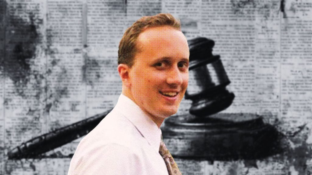 Douglass Mackey in a white shirt and patterned tie with a background featuring a large black judge's gavel and a backdrop of newspaper print.