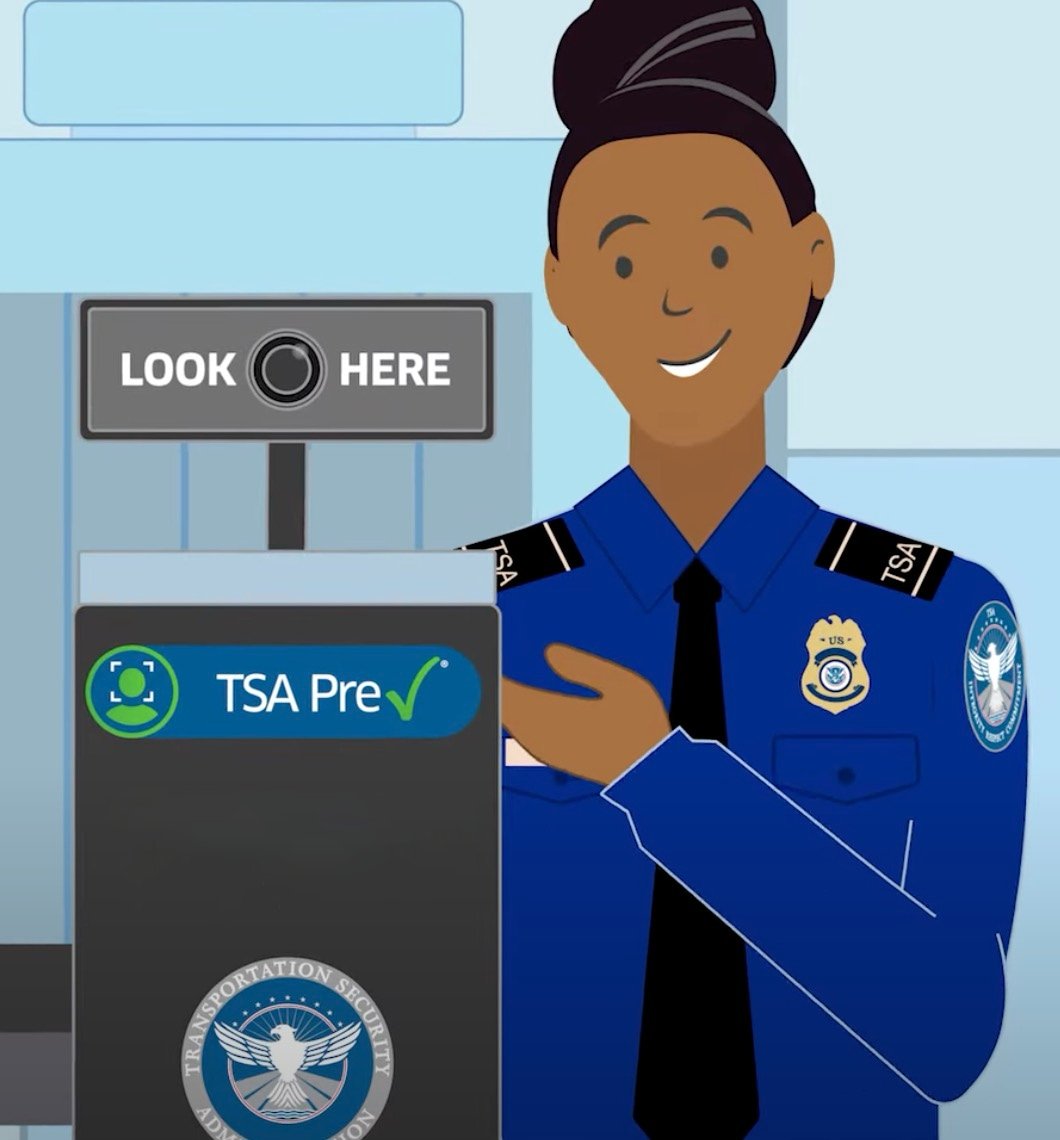 Illustration of a smiling Transportation Security Administration officer in a blue uniform pointing to a TSA Pre✓ sign with a camera and text reading "Look Here" above it at a security checkpoint.