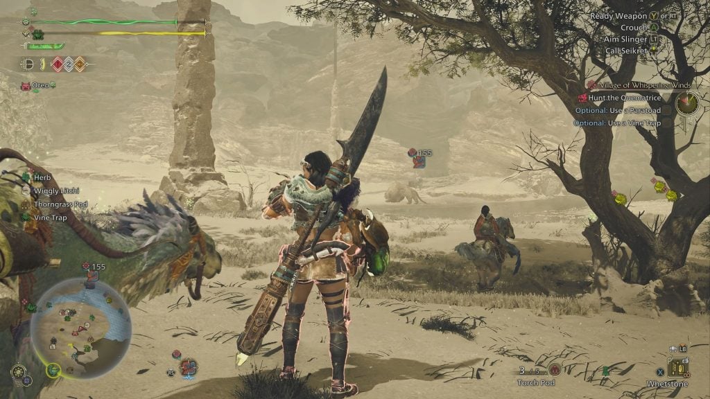 Video game screenshot showing a player character holding a large sword facing a desert-like area with rocky formations, a tree, and a creature named Quematrice in the distance, with another character on horseback and a bird-like companion visible nearby, along with game HUD elements displaying health, items, and objectives.