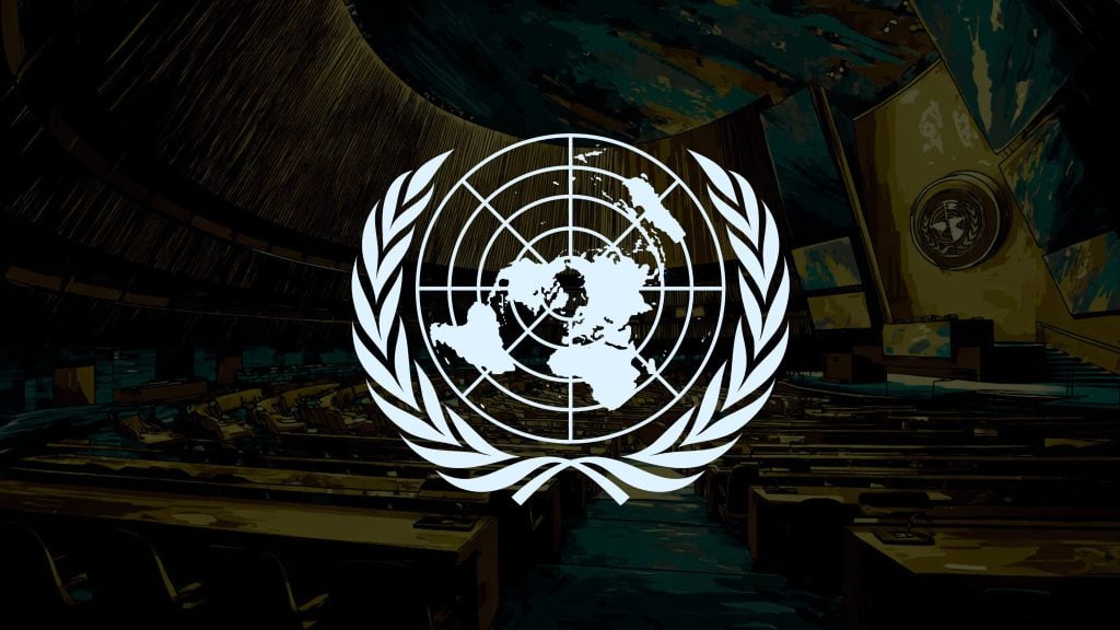 The United Nations emblem featuring a world map surrounded by olive branches superimposed over a dimly lit assembly hall with rows of desks and chairs and a large emblem on the wall.