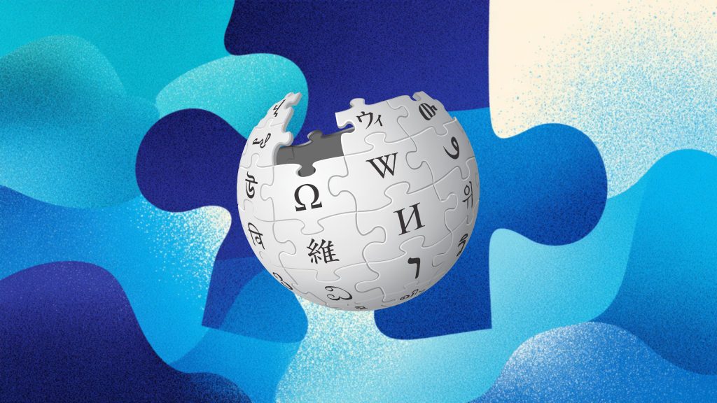 Partially assembled white jigsaw-globe Wikipedia logo with black multilingual characters and missing top pieces, set against an abstract layered blue puzzle-piece background.