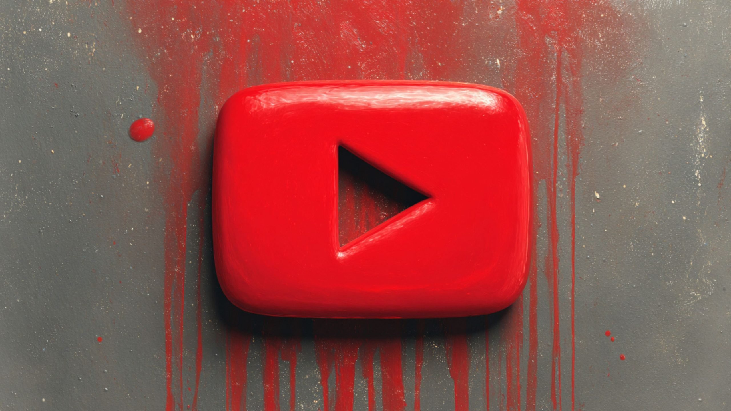 Glossy three-dimensional red YouTube play button with a triangular cutout centered on a gray textured wall, surrounded by red paint splatters and vertical drips.
