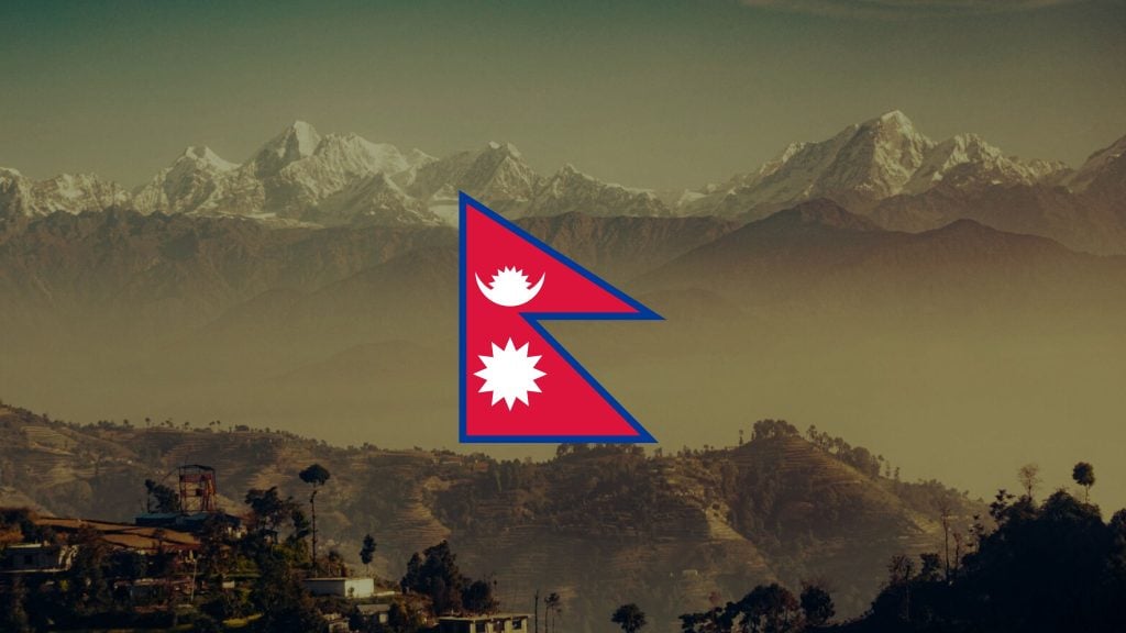 Red, blue-edged double-pennon flag of Nepal with white stylized moon and sun centered over a hazy landscape of terraced hills and distant snow-capped Himalayan peaks.