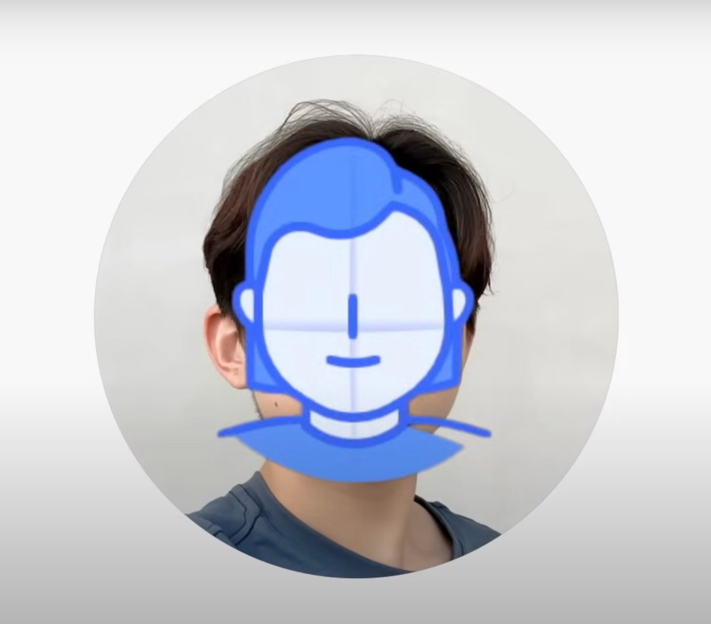 Circular profile-style photo of a person with brown hair wearing a blue shirt, their face obscured by a semi-transparent blue cartoon avatar overlay against a light gray background.