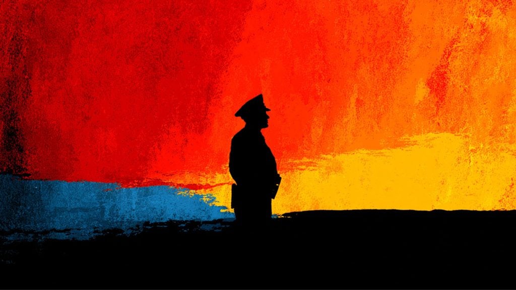 Silhouette of a uniformed officer in a peaked cap standing on a black horizon against a vivid red, orange and yellow abstract sky with a strip of blue near the horizon.