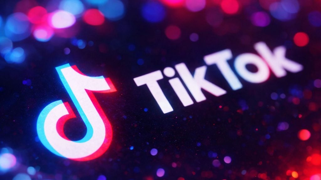 TikTok logo and wordmark glowing in neon red and blue against a dark bokeh background.