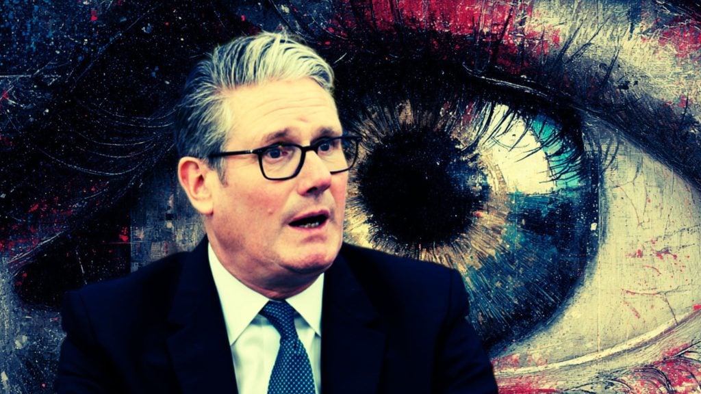 Starmer in suit and tie wearing glasses looks surprised against a large painted eye mural background.