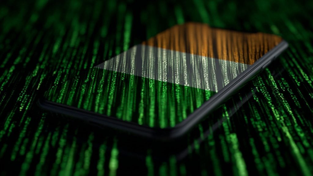 Smartphone with orange-white-green tricolour on its screen, overlaid by cascading green code lines on a dark reflective surface