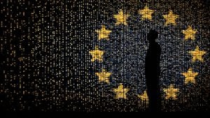 Silhouette of a person standing before a digital wall of yellow stars and blue lights forming a ring on a dark background