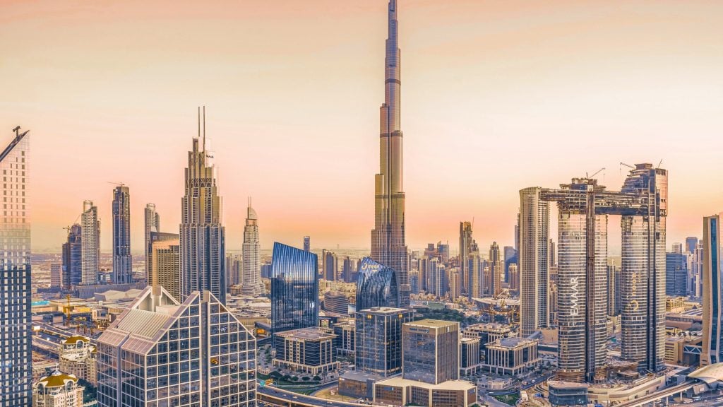 Dubai skyline at sunset dominated by the Burj Khalifa and surrounding modern glass skyscrapers.