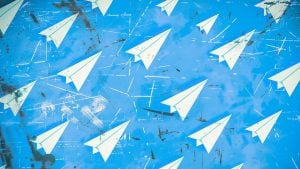 White paper airplanes flying across a textured bright blue sky with white streaks and grunge marks