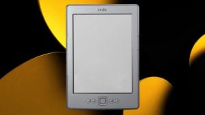 Silver Amazon Kindle e-reader with blank screen and navigation buttons, centered on black background with yellow abstract shapes